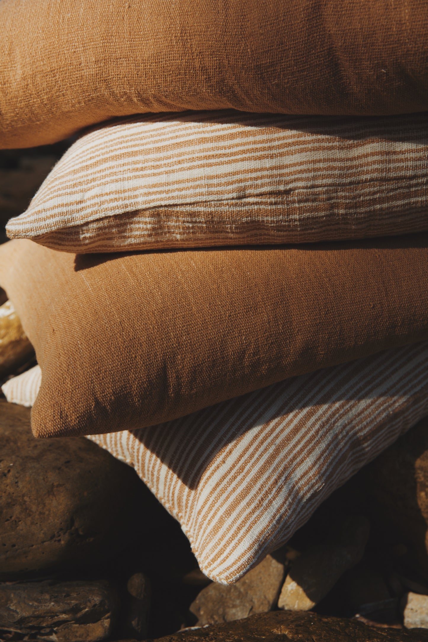 Stack of brown and beige striped pillows on a stone surface