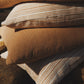 Stack of brown and beige striped pillows on a stone surface