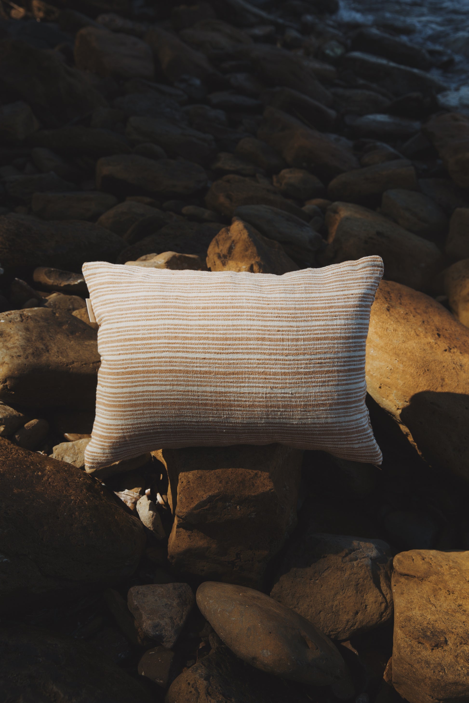 Striped pillow on a rocky surface near water