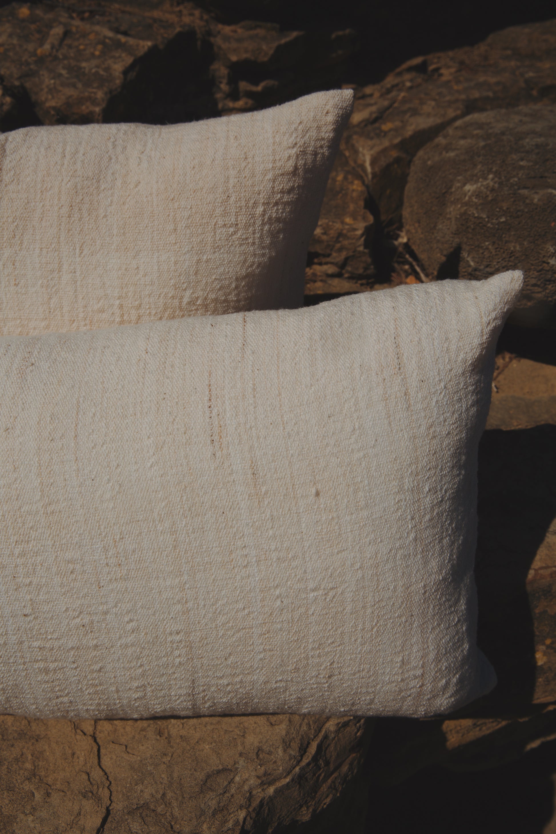 Two textured pillows on a stone surface