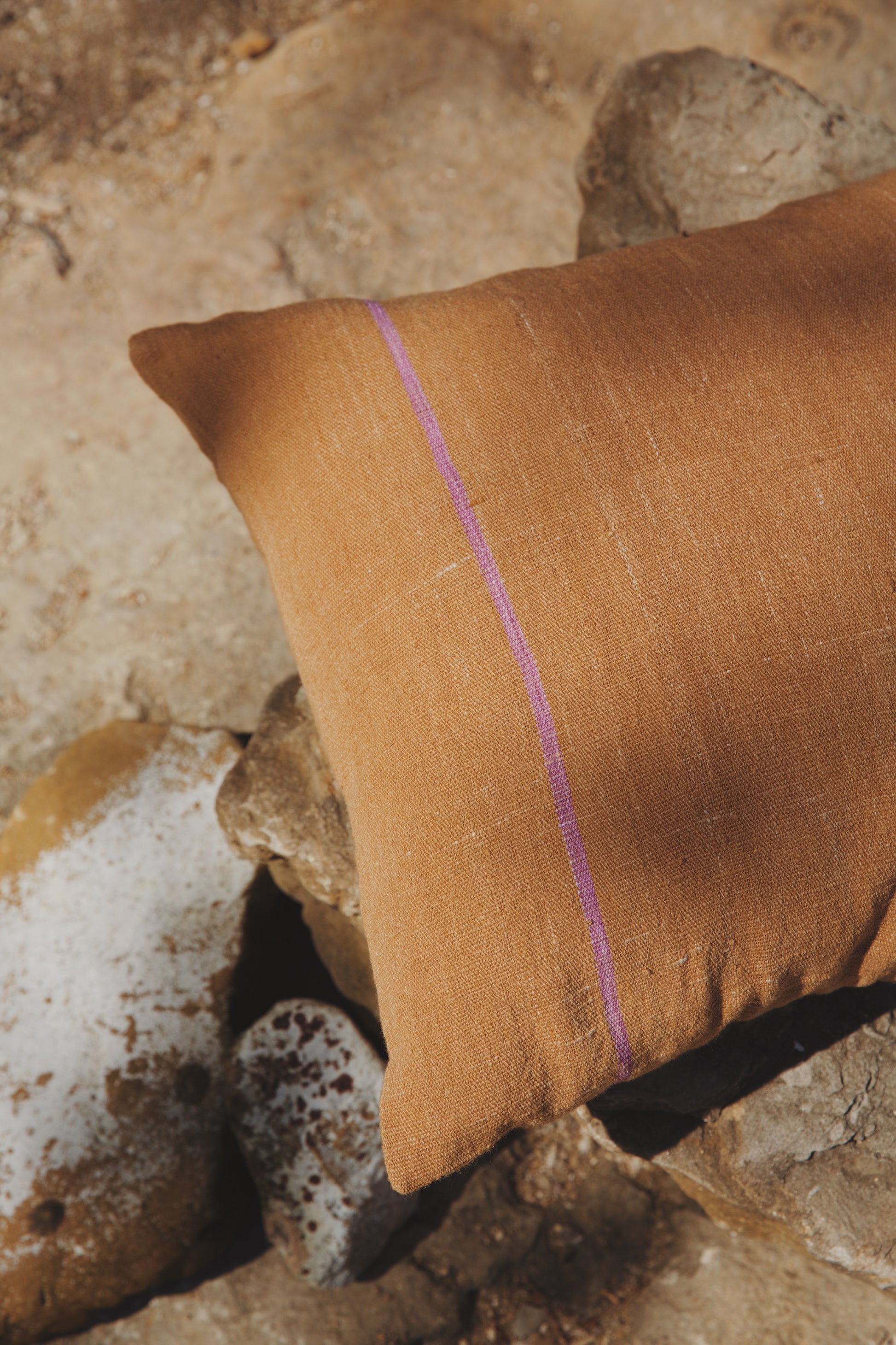 Brown pillow with a purple line of tixinda (caracol purpura) on a stone surface