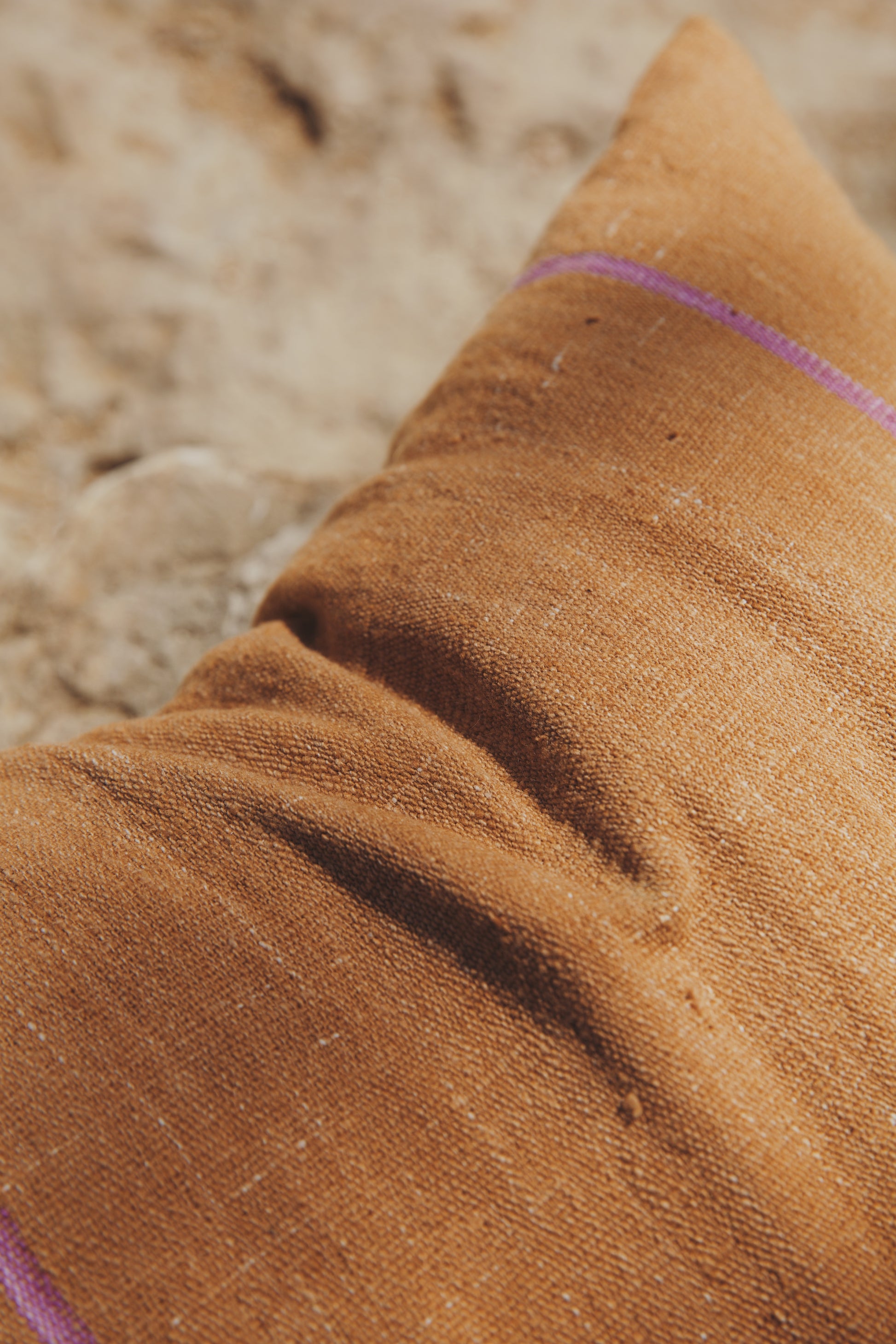 Close-up of brown fabric and line of tixinda with a blurred natural background