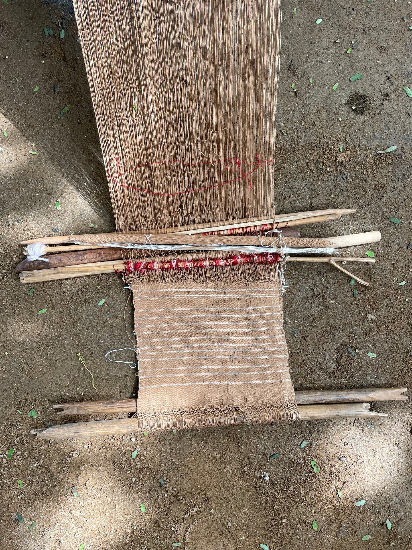 Handmade woven fabric on backstrap loom on a sandy surface