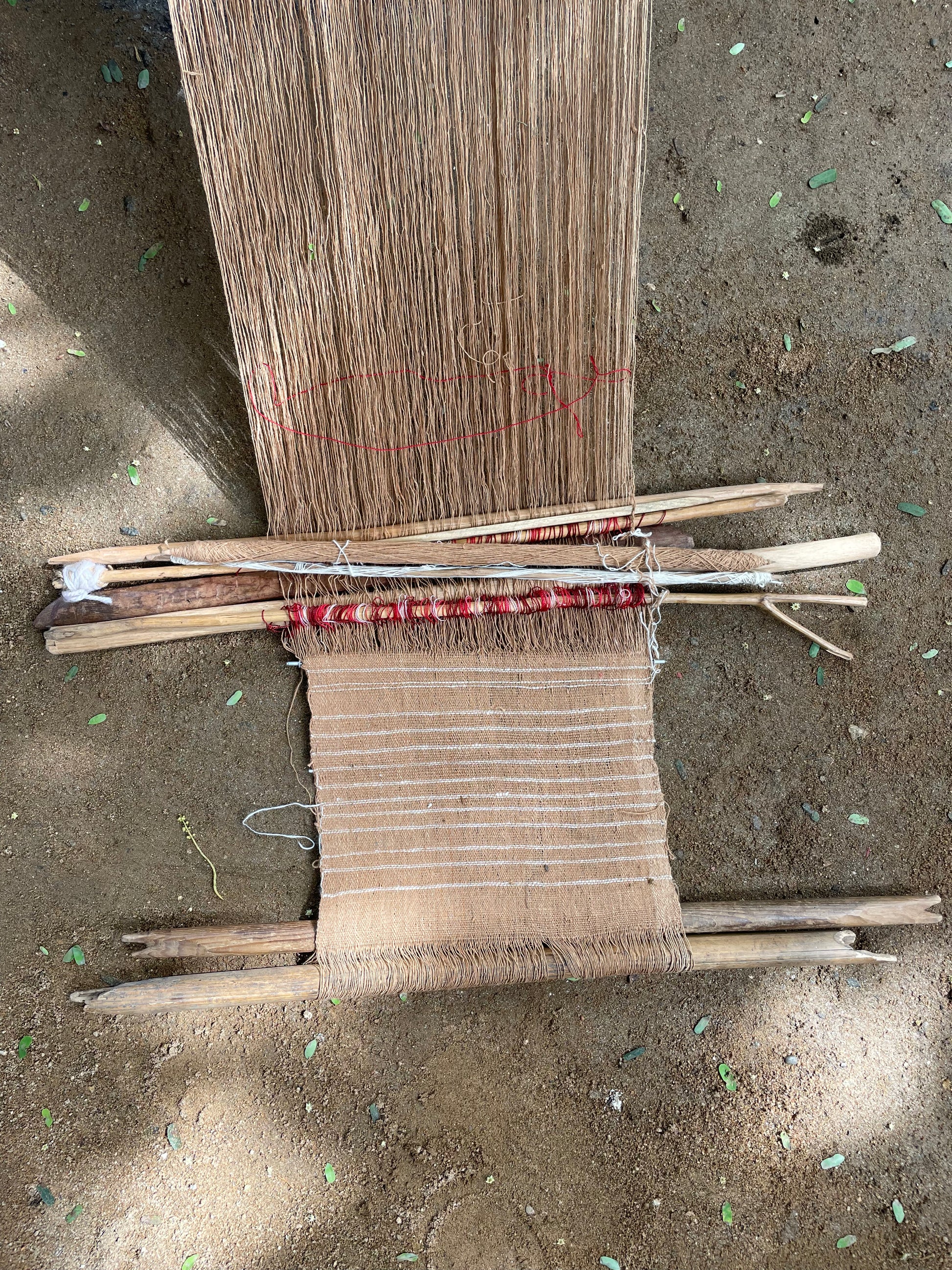 Handmade woven fabric on backstrap loom on a sandy surface